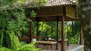 A traditional wooden gazebo with a tiled roof, surrounded by lush greenery and a stone pathway. - Nyne Hotels Leela Walauwwa - Induruwa (Induruwa)