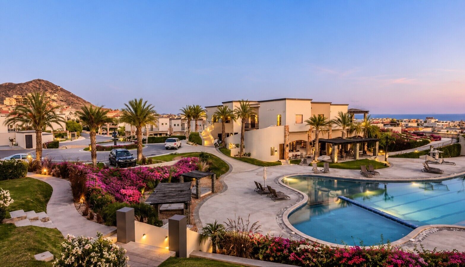 A resort with a swimming pool, palm trees, and modern buildings.