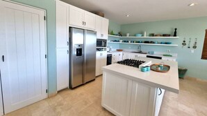 Une cuisine moderne avec des meubles blancs, des appareils en acier inoxydable et un îlot central.