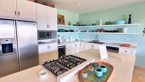 Une cuisine moderne avec des armoires blanches, un réfrigérateur en acier inoxydable, un four encastré et une cuisinière à gaz.