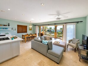 A living room with a sofa, a TV, and a dining area with chairs and a table. - Hillside Ocean Views: Private Terrace & Pool (Cabo San Lucas)