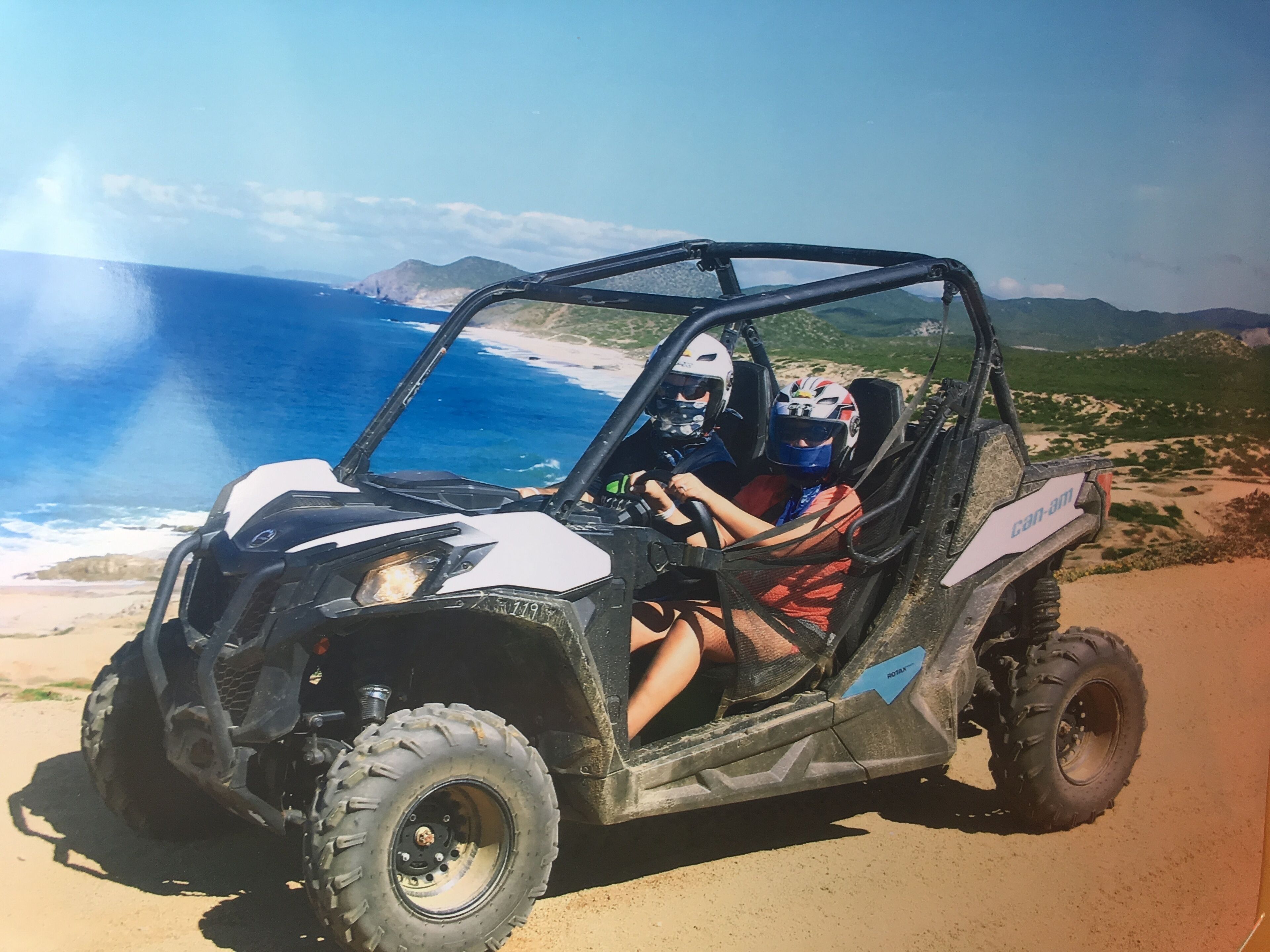 Un véhicule tout-terrain Can-Am sur un chemin de terre, avec une vue sur la côte.