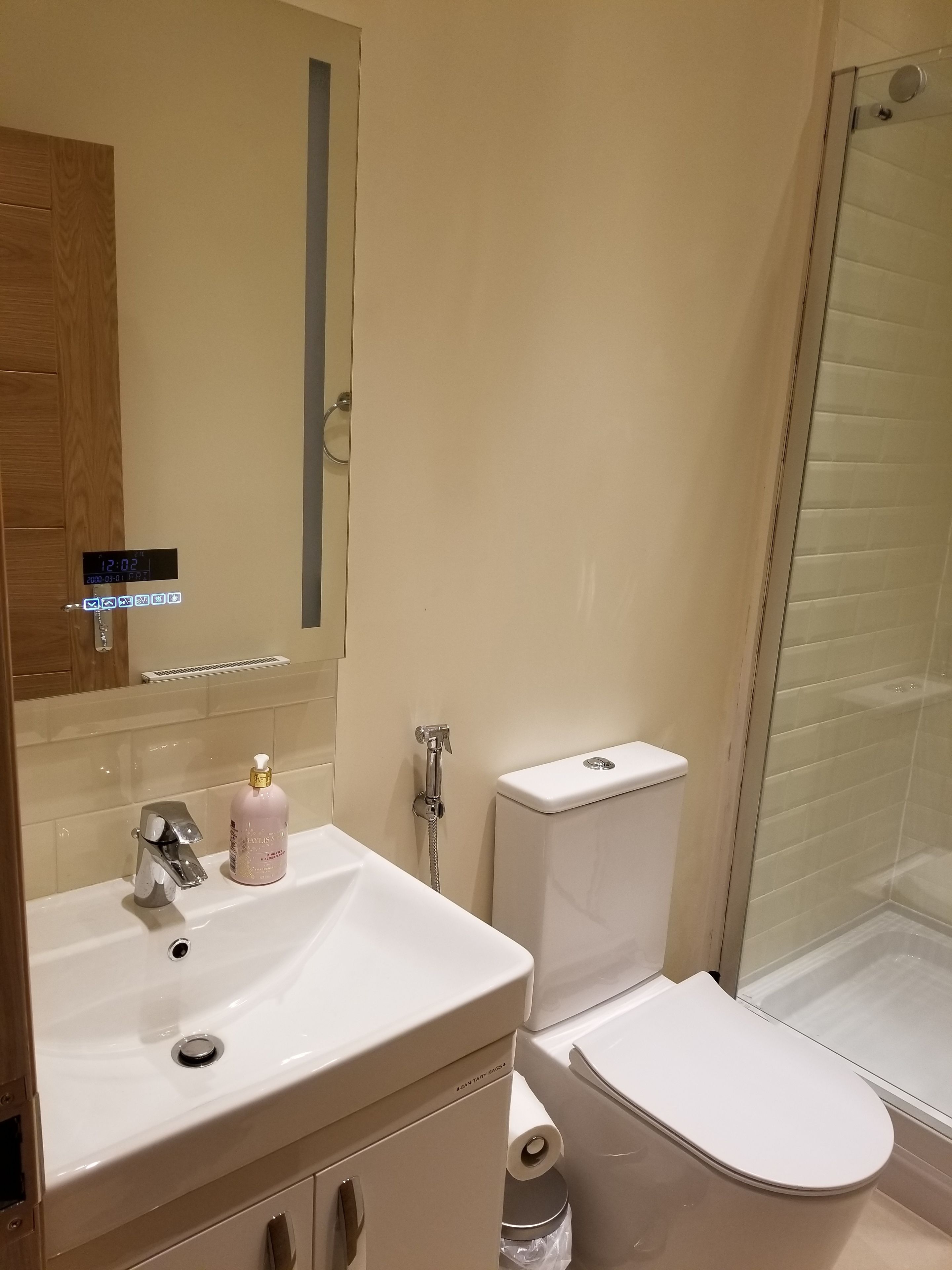 A bathroom with a white sink, a toilet, and a glass shower enclosure.