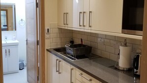 Une cuisine moderne avec des meubles blancs, un évier en acier inoxydable et un four à micro-ondes.