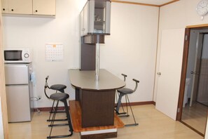 Eine kompakte Küche mit Mikrowelle, Kühlschrank und einer kleinen Bar mit Barhocker.