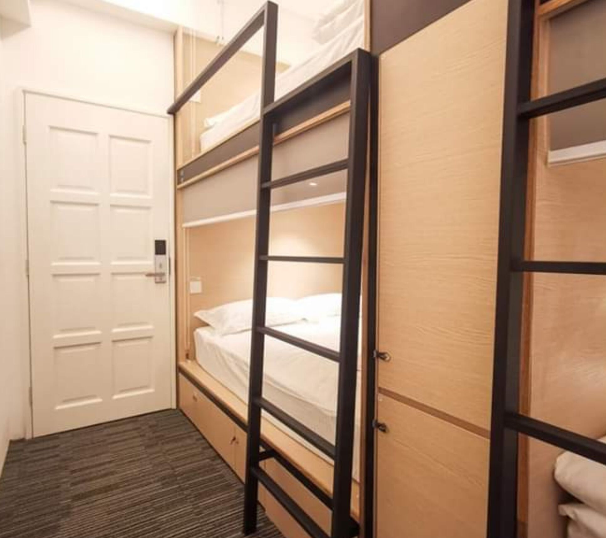 A compact room with a bunk bed, a wooden wardrobe, and a door.