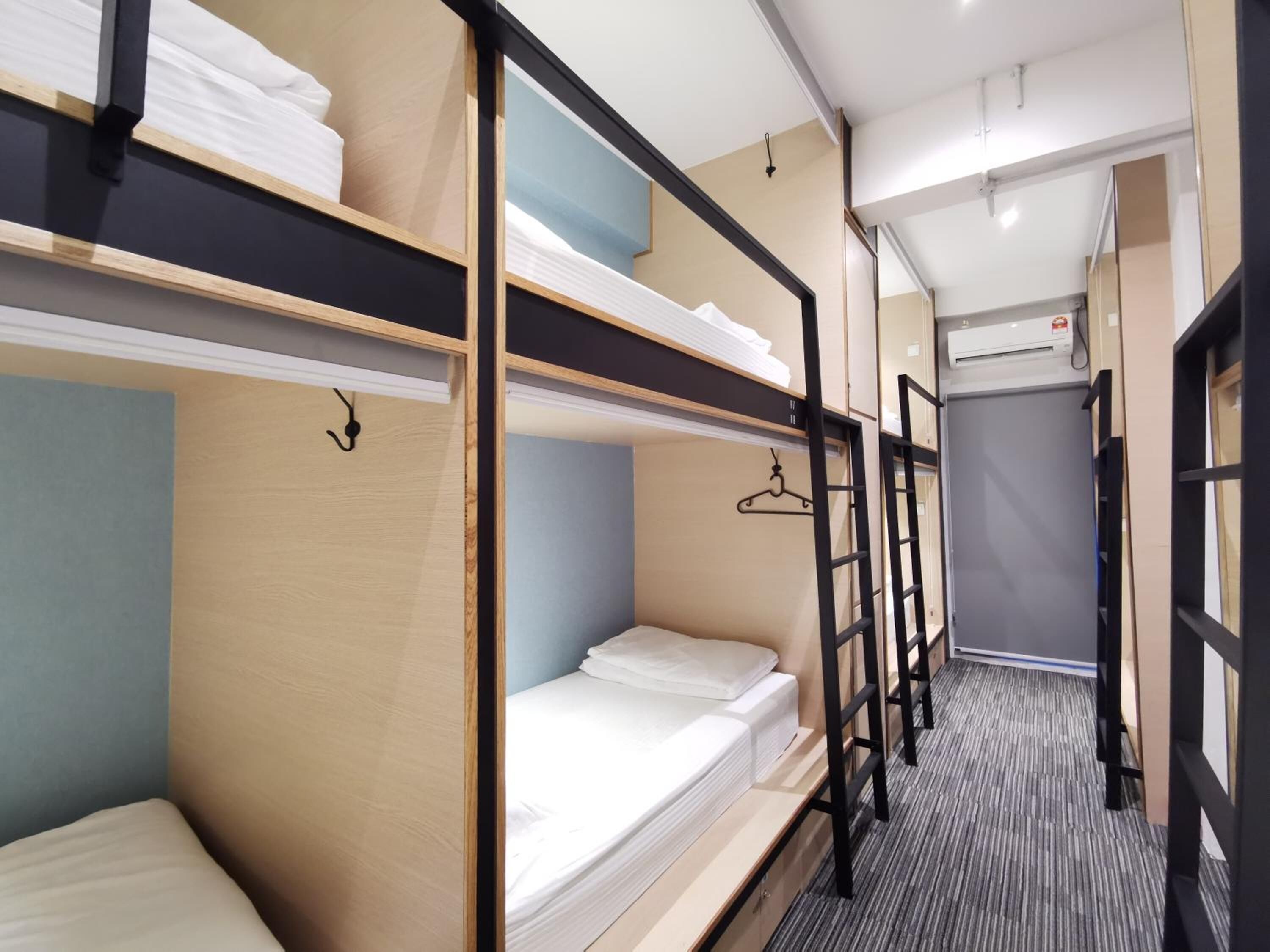 A hotel room with bunk beds, a small desk, and a window.