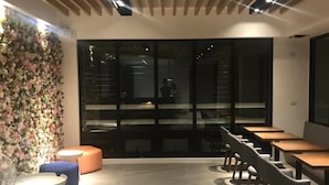 A modern interior with a long table and chairs, a floral wall, and large windows.