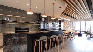A modern kitchen with a marble countertop, pendant lights, and bar stools.
