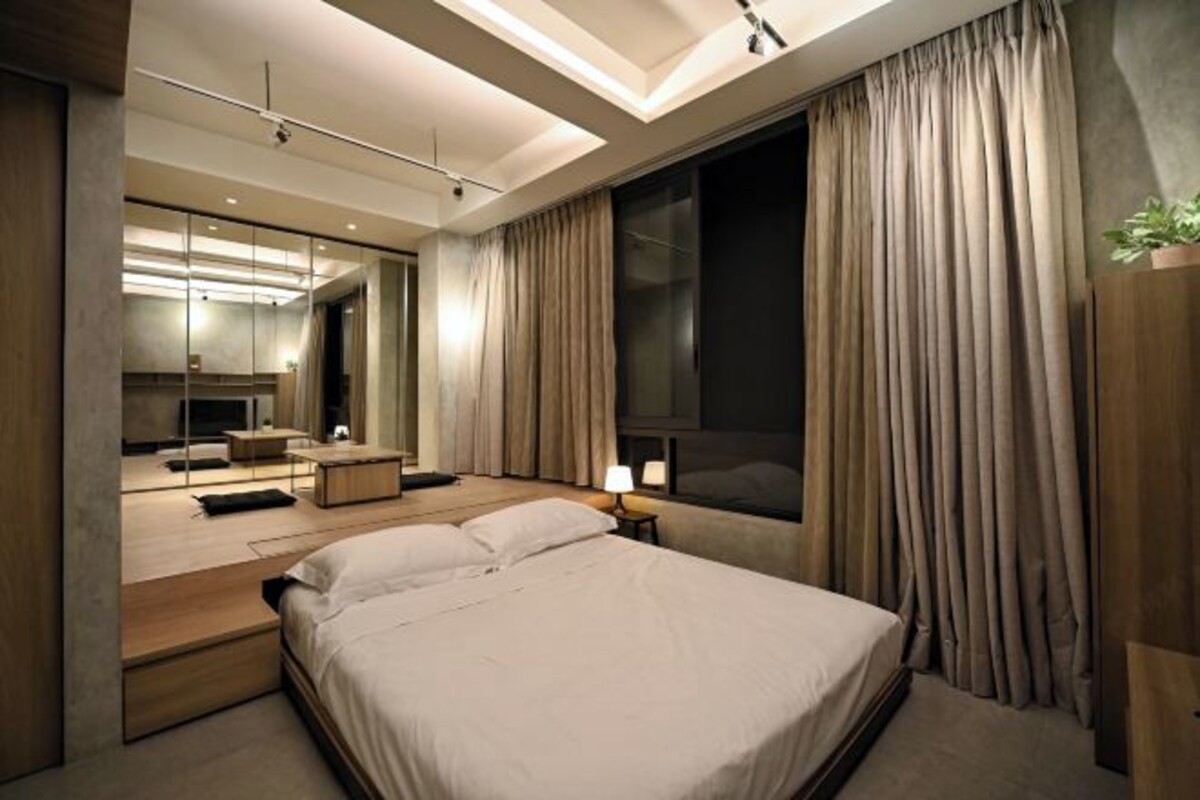 Une chambre d’hôtel moderne avec un grand lit, un bureau, un miroir et une fenêtre avec des rideaux.