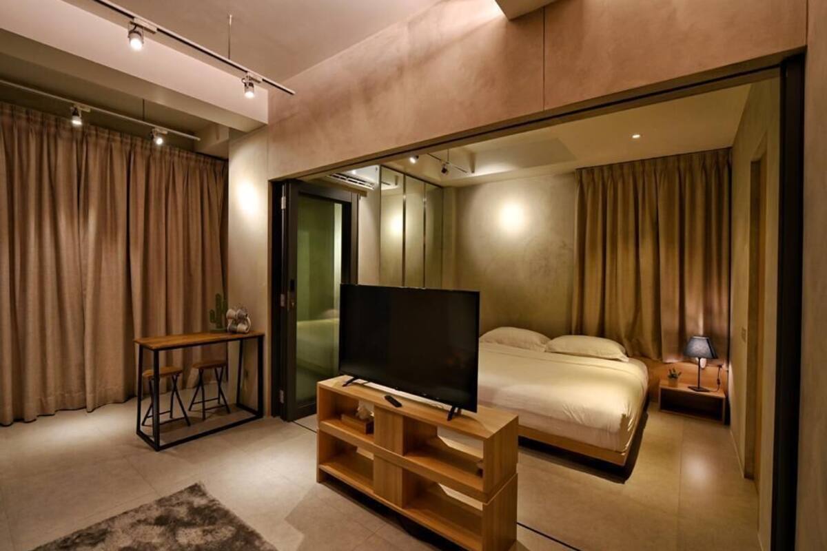 A modern bedroom with a large bed, a TV on a wooden stand, and a sliding door leading to another room.