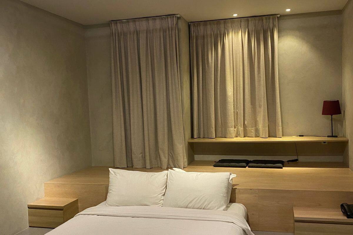 A modern bedroom with a bed, bedside tables, a TV, and curtains.