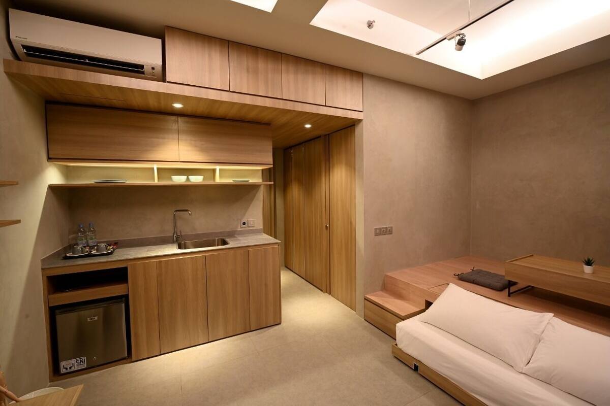 A compact room with a kitchenette, a bed, and a small seating area.