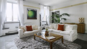 A modern living room with two white sofas, a coffee table, and a large window with sheer curtains. - Magia at Colosseum (Rome)