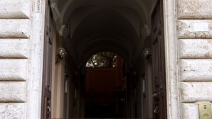 An entrance with a stone facade, a dark wooden door, and a metal gate. - Magia at Colosseum (Rome)