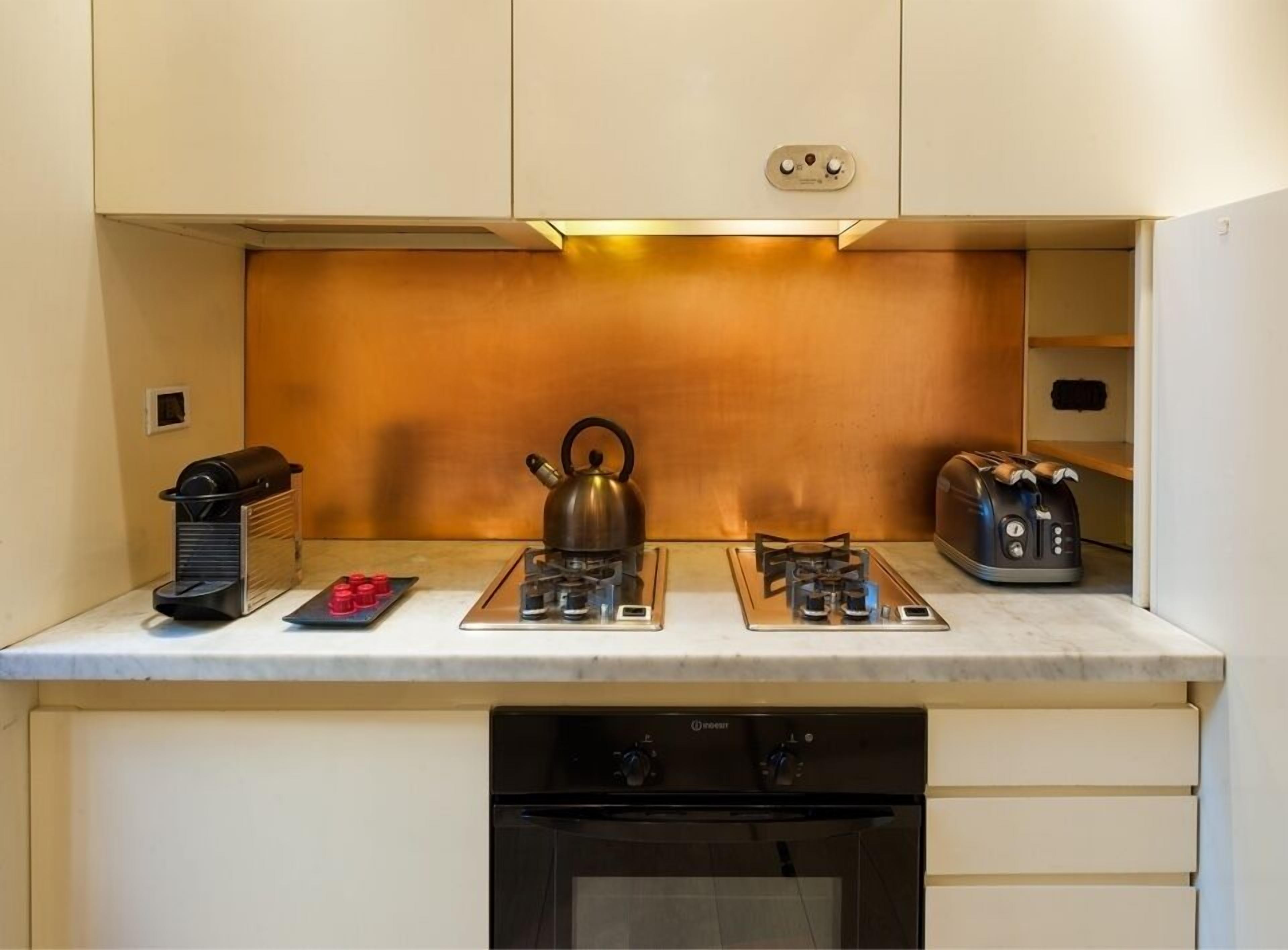 Een kleine keuken met een gasfornuis, waterkoker, broodrooster en koffiezetapparaat.