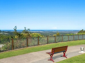 Situated on a paved walkway, this bench offers a serene view of a body of water and distant landforms.