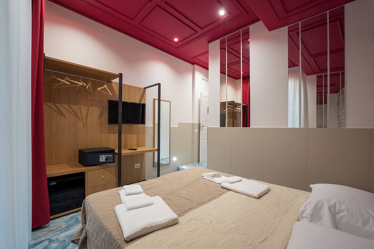 Une chambre d’hôtel avec un lit, une télévision, une armoire et un miroir.