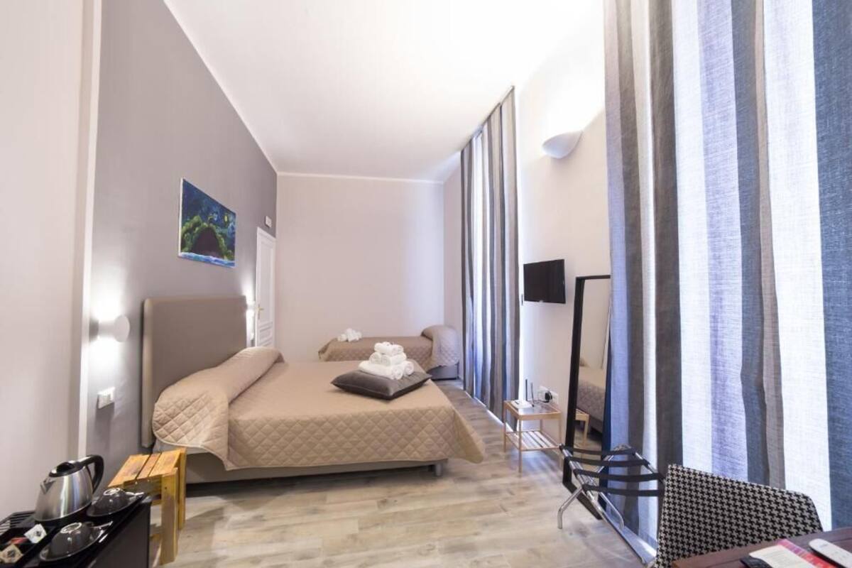 Une chambre d’hôtel équipée d’un lit, d’une petite table avec une bouilloire, d’une chaise et d’un téléviseur à écran plat.
