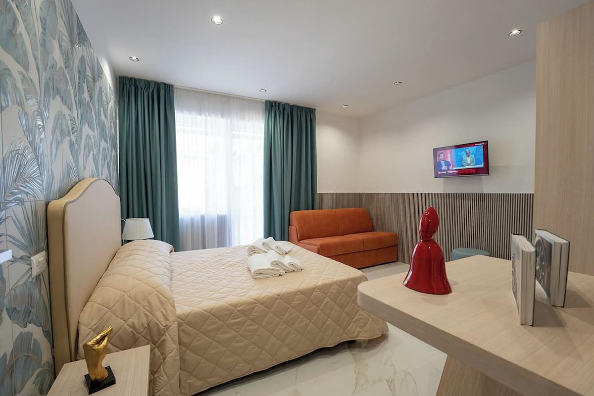 Une chambre d’hôtel comprenant un lit, un bureau, une chaise, un téléviseur et une statue décorative.
