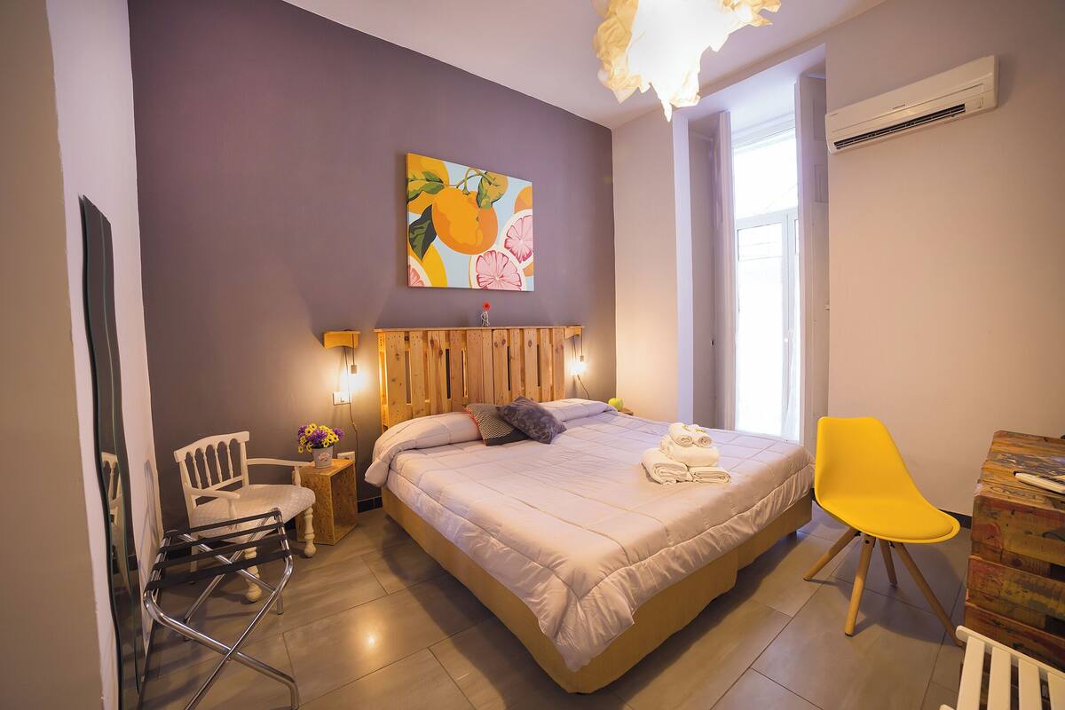 Une chambre à coucher avec un lit, une table de chevet, une chaise et un tableau accroché au mur.