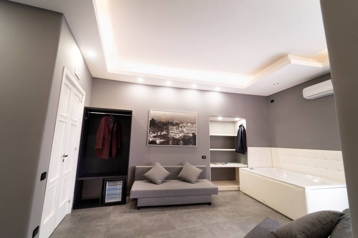 Une salle de bain moderne avec un canapé gris, une grande baignoire et un climatiseur fixé au mur.