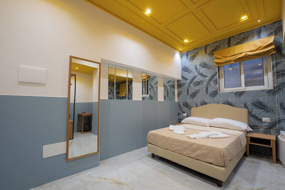 Une chambre à coucher avec un lit, un miroir et une fenêtre avec des rideaux.