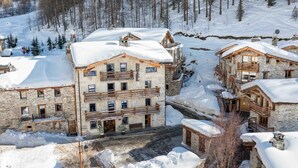 A snow-covered lodge with multiple balconies and stone architecture. - Chalet Hôtel du Fornet (Val-d'Isere)