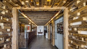 A hallway with wooden paneling on the walls and ceiling, a reception desk, and a clock on the wall. - Chalet Hôtel du Fornet (Val-d'Isere)