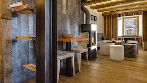 A cozy living room with a fireplace, wooden beams, and a stone wall. - Chalet Hôtel du Fornet (Val-d'Isere)