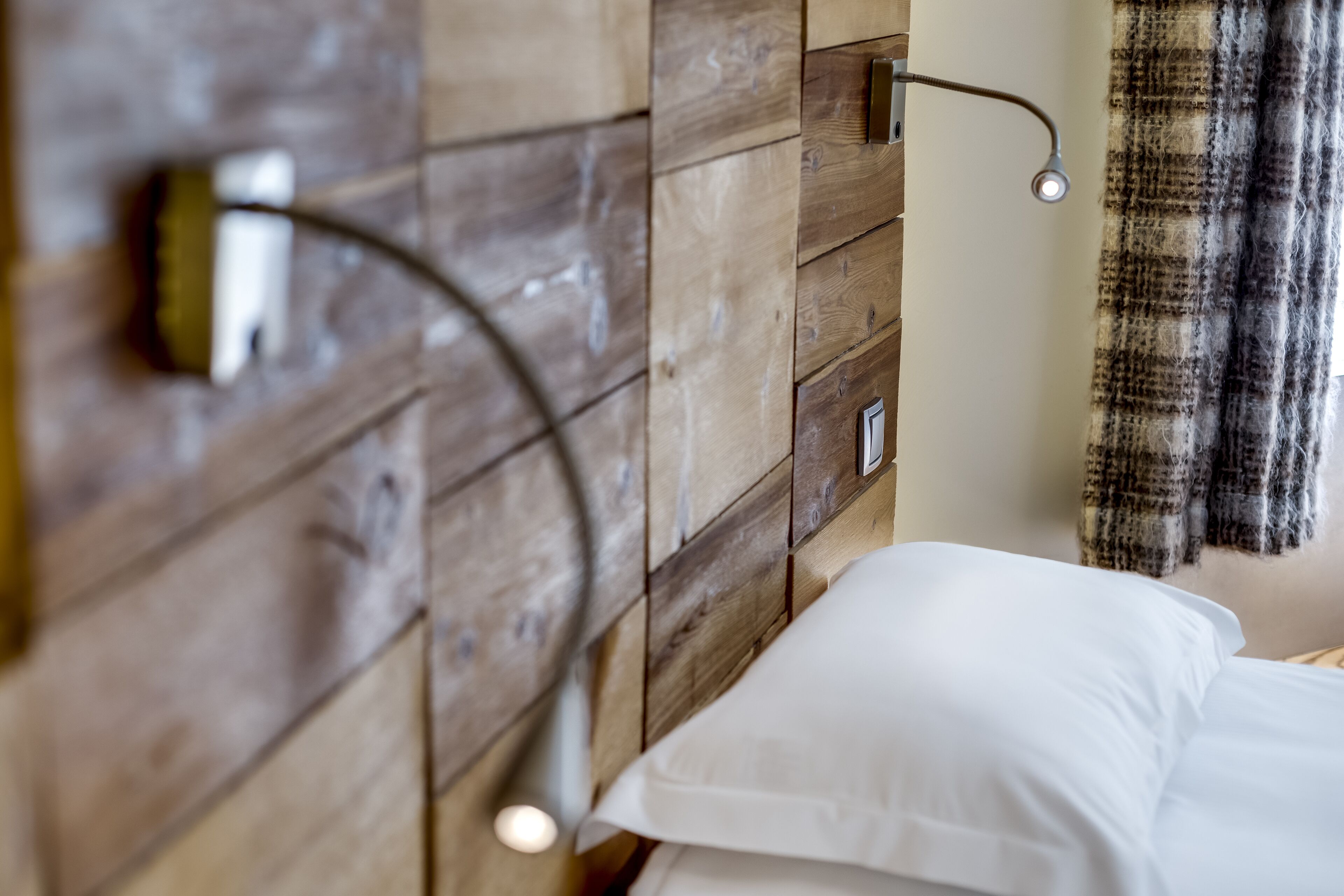 A wooden headboard with a light fixture and a bedside table with a white pillow.