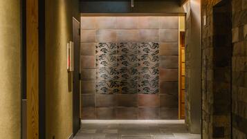 A hallway with a patterned wall, a wooden door frame, and a stone wall on the right.