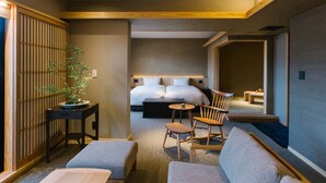 A hotel room with a bed, a seating area with a table and chairs, a small table with a cup, and a potted plant. - Shikikaboku (Kyoto)