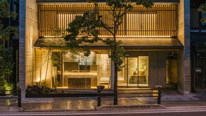 A modern building with a warm-lit entrance, large windows, and a visible reception area. - Shikikaboku (Kyoto)