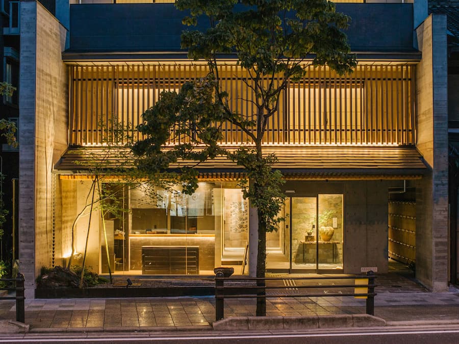 A modern building with a warm-lit entrance, large windows, and a visible reception area.