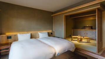 Een moderne hotelkamer met een groot bed, een houten hoofdeinde en een zithoekje met een tafel en stoelen.