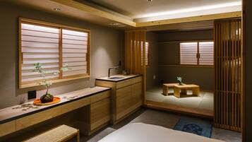 A compact bedroom with a wooden desk, a bed, and a small sitting area.