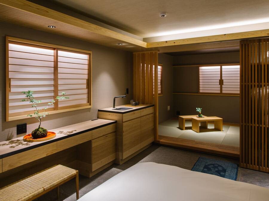 A compact bedroom with a wooden desk, a bed, and a small sitting area.