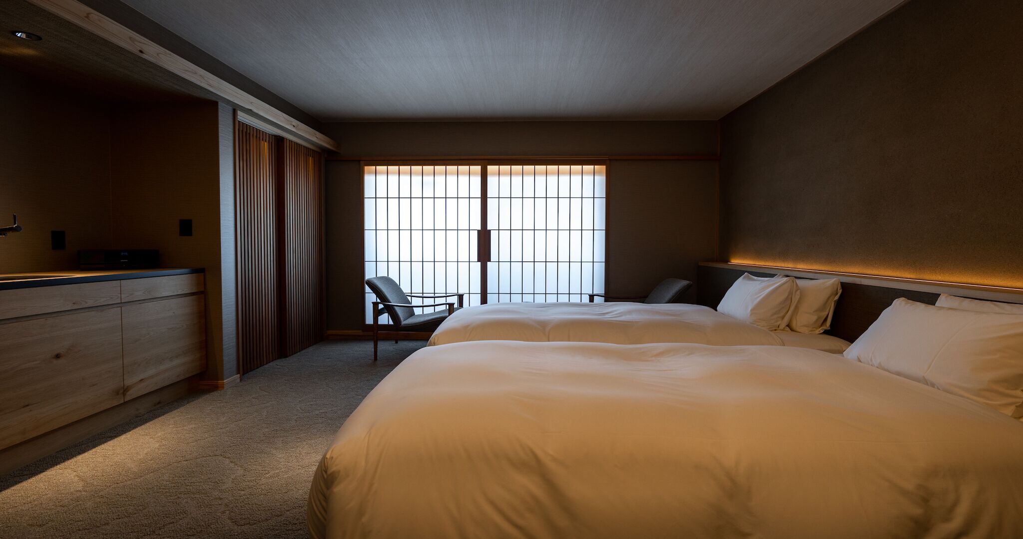 A hotel room with a large bed, a desk, and a chair.