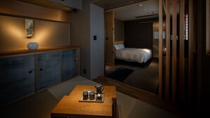 A modern hotel room with a wooden desk, a bed, and a sliding door leading to another room. - Shikikaboku (Kyoto)