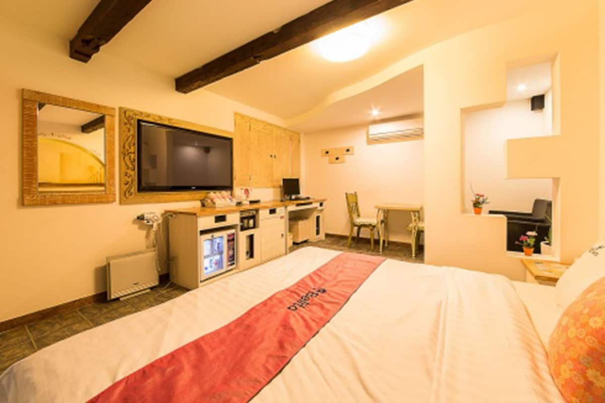 Une chambre d’hôtel avec un lit, une télévision, un bureau et une chaise.
