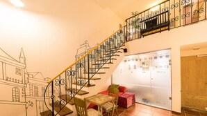 A staircase with ornate metal railings, a dining area with a table and chairs, and a view of a building through a glass door. - Belita N Goodtime Drive-in Motel (Paju)