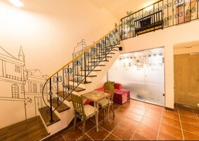 A staircase with ornate metal railings, a dining area with a table and chairs, and a view of a building through a glass door.