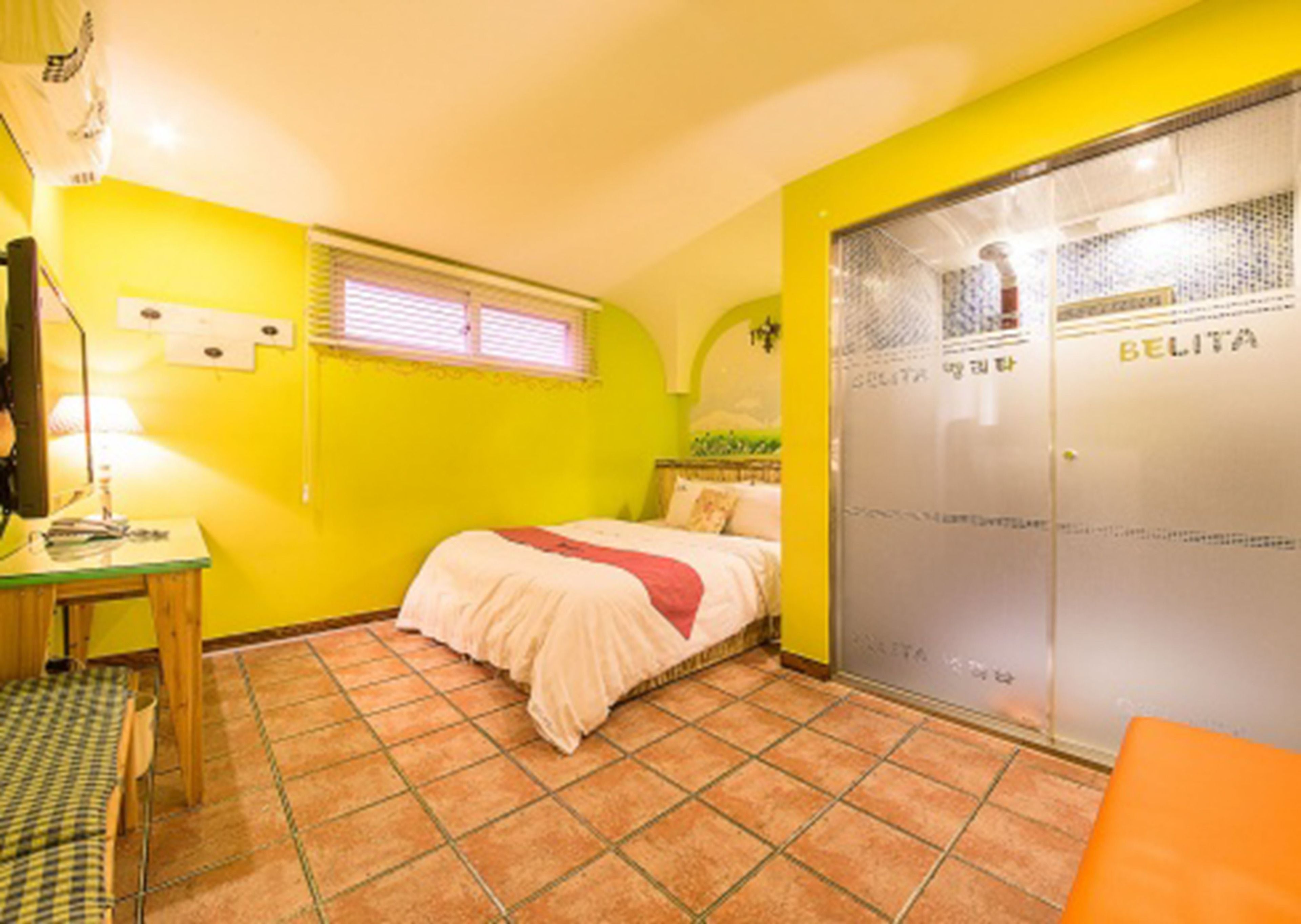 Una habitación con cama, escritorio, silla, armario y ventana.