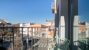 A balcony with a view of a city street, a parked car, and a green chair. - Sweett | Callao III - Two Bedroom Apartment, Sleeps 4 (Barcelona)