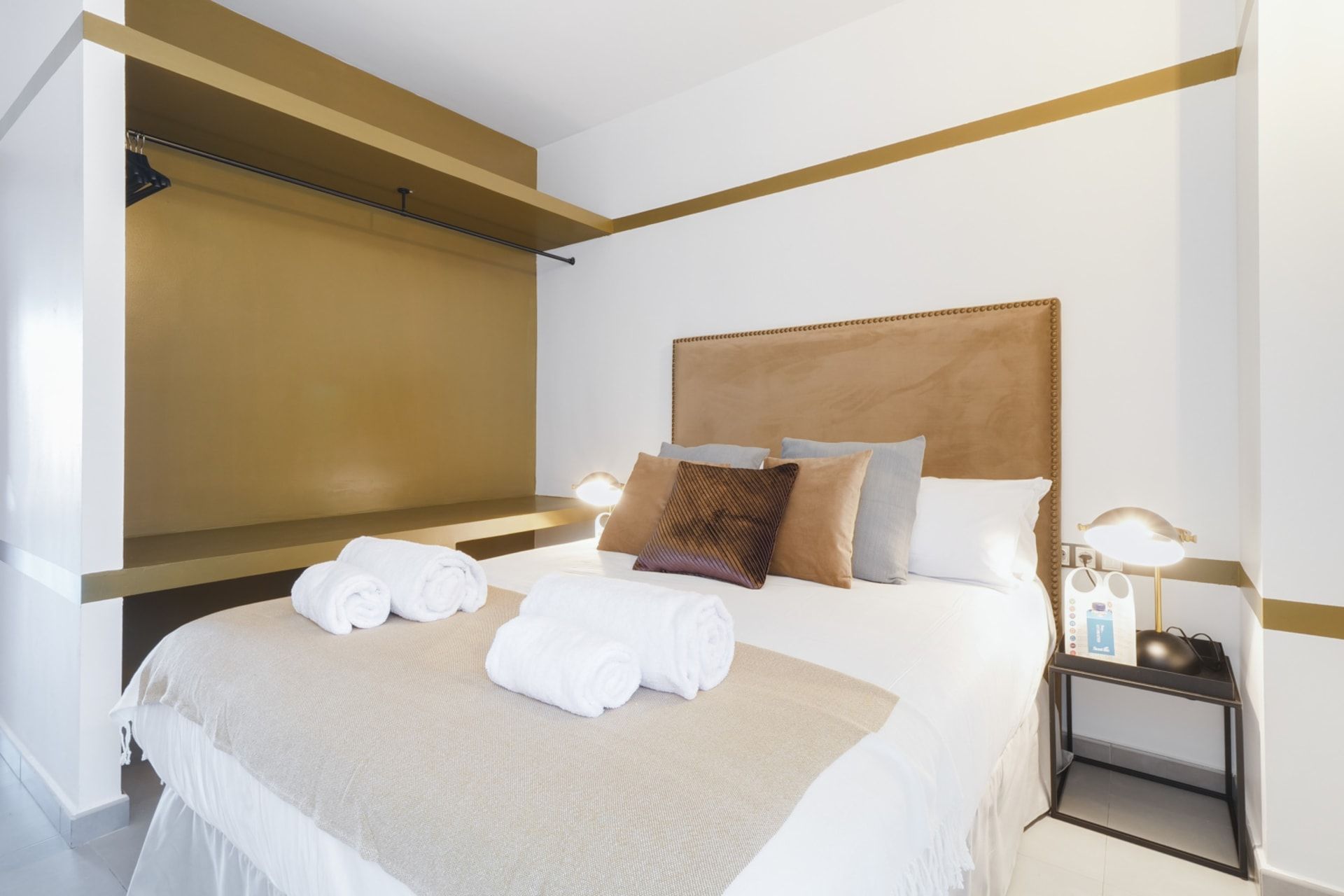 Ein Hotelzimmer mit einem Bett, Kissen, einem Nachttisch mit Lampe und Handtüchern.