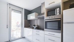 A modern kitchen with white cabinets, a built-in oven, a microwave, and a coffee maker. - Sweett | Callao III - Two Bedroom Apartment, Sleeps 4 (Barcelona)