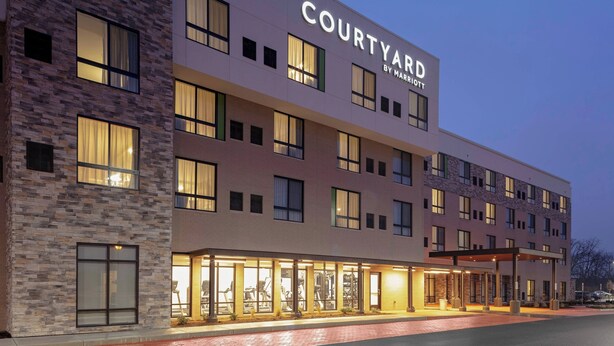 A Courtyard by Marriott hotel with a modern design, featuring a brick facade, multiple windows, and a well-lit entrance area. - Courtyard by Marriott Cincinnati Mason (Mason)