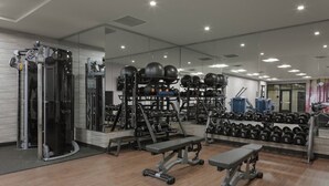 A modern gym with weightlifting equipment, benches, and a mirrored wall. - Courtyard by Marriott Cincinnati Mason (Mason)
