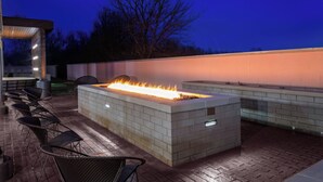 An outdoor patio with a built-in fire feature, seating, and a brick wall. - Courtyard by Marriott Cincinnati Mason (Mason)